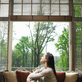 woman looks through window blinds